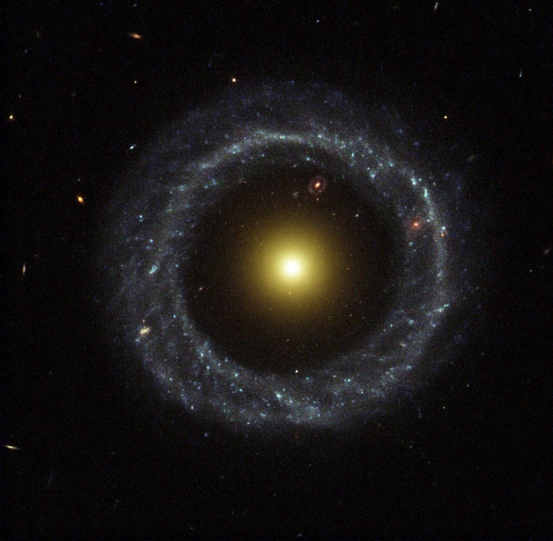 A nearly perfect ring of hot, blue stars pinwheels about the yellow nucleus of an unusual galaxy known as Hoag's Object