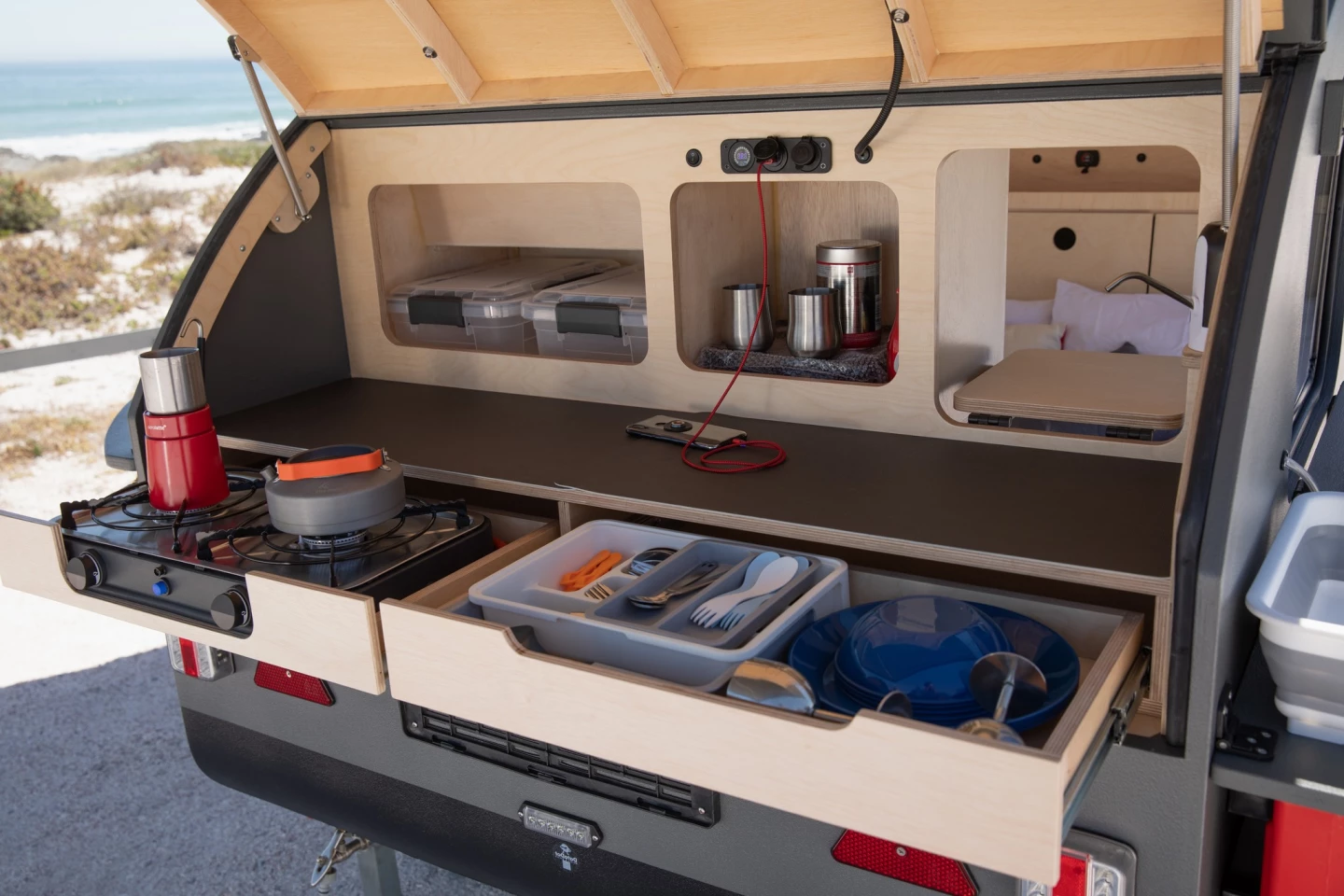Red Gecko keeps the galley compact and functional, offering a drawer large enough to hold the portable dual-burner stove, a separate utensil/dishware drawer, a full-width worktop, storage shelves and a compact gravity water tap in the far right corner