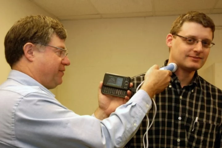 Dr William Richard (left) takes an ultrasound probe of colleague David Zar's carotid artery with smartphone-compatible USB ultrasound probe he designedPhoto credit: David Kilper/WUSTL Photo