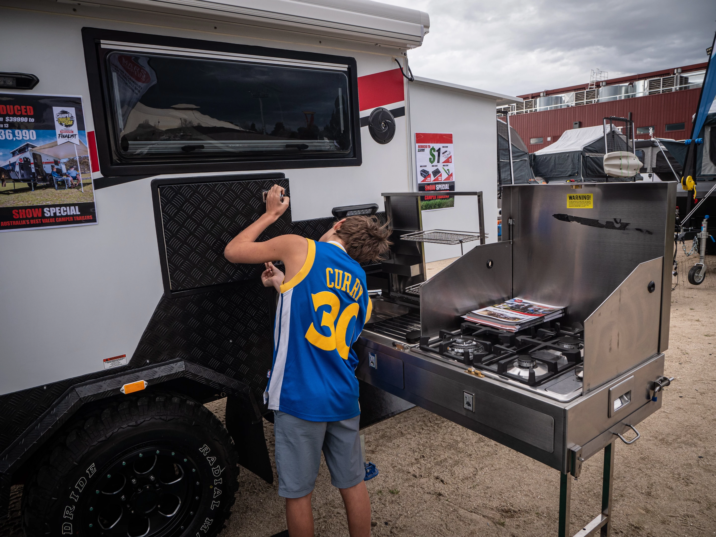 The main slide-out kitchen area has a four-burner stove and sink