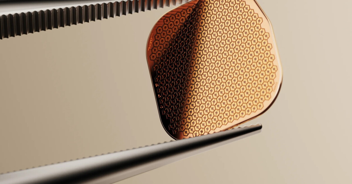 A small rectangular microchip with a grid of tiny photovoltaic pixels, shown next to a pair of specialized glasses with a camera and projector mounted on the frame.