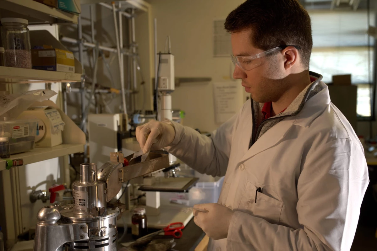Graduate student Paul Savas feeds raw plastic into a crusher to prepare it for pyrolysis