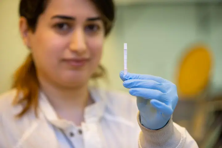 University of Cincinnati research assistant Shima Dalirirad holds up a test strip that can measure stress biomarkers