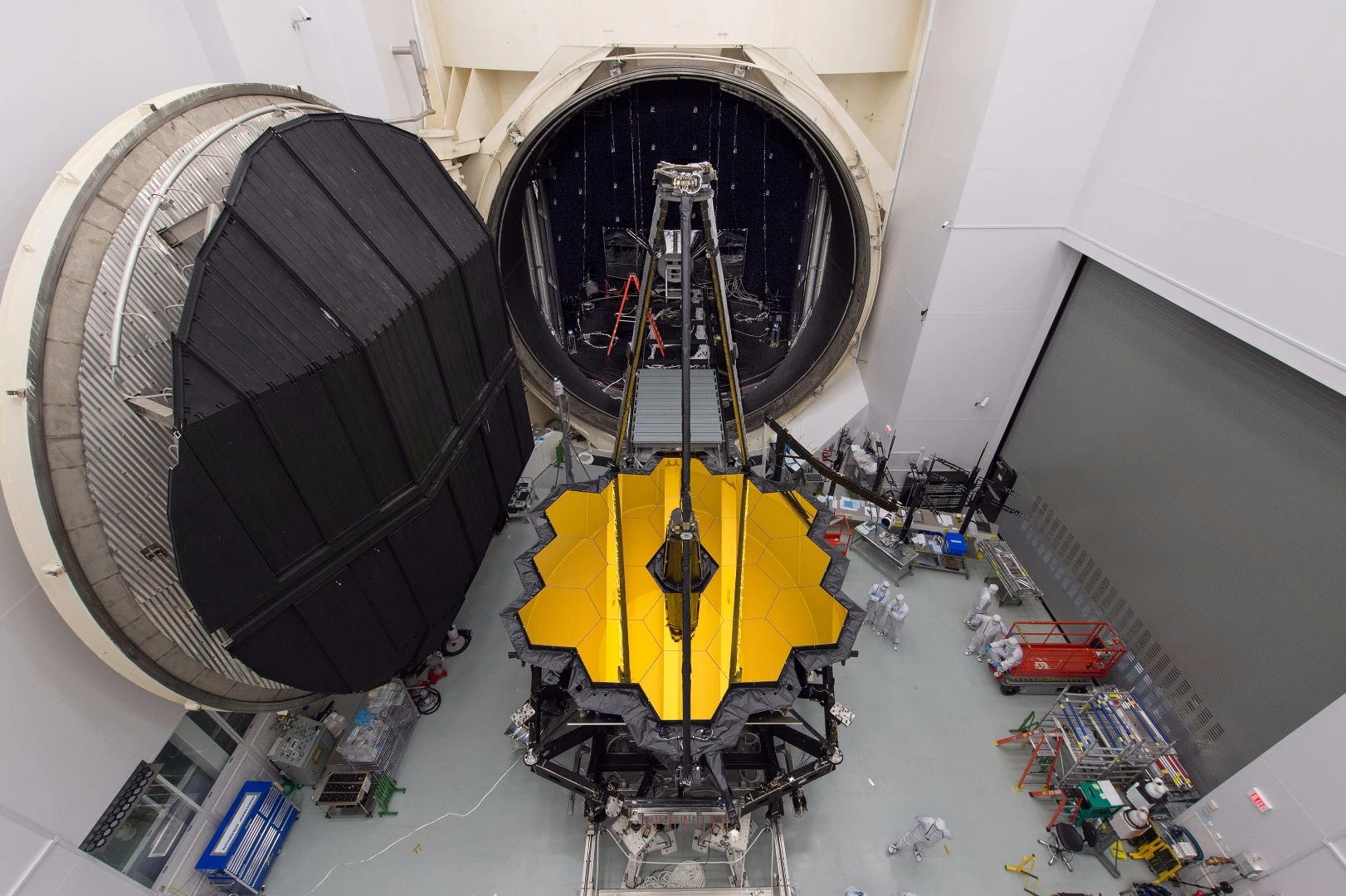 The James Webb Space Telescope sitting in front of a giant thermal–vacuum chamber in NASA’s Johnson Space Center