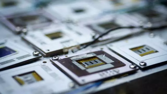 A batch of perovskite solar cells sit under bright light in the accelerated aging chamber