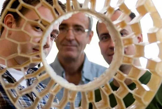 University of Wisconsin-Madison mechanical engineering graduate students Eric Foltz (left) and Nick Newman (right), along with faculty adviser Tim Osswald (center), look through the honeycomb pattern of an early prototype of a non-pneumatic tire they help