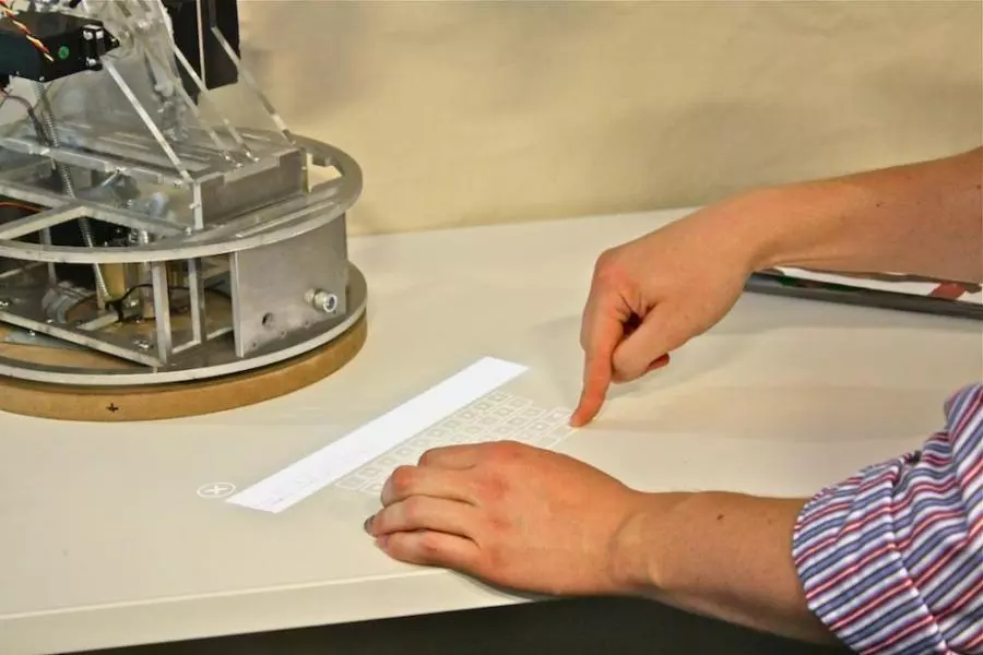 A user types a message using a keyboard projected by the LuminAR Bulb