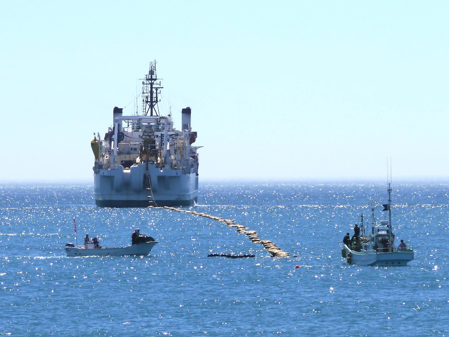 The brown bag-like objects are floats that hold the cable up so it doesn't drag on the ocean floor – they are removed after the cable is run