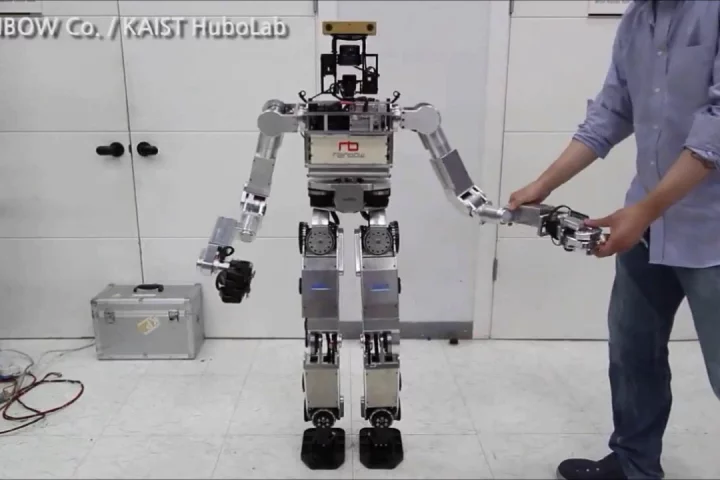 A researcher manipulates DRC-HUBO's arms to demonstrate its compliant joints