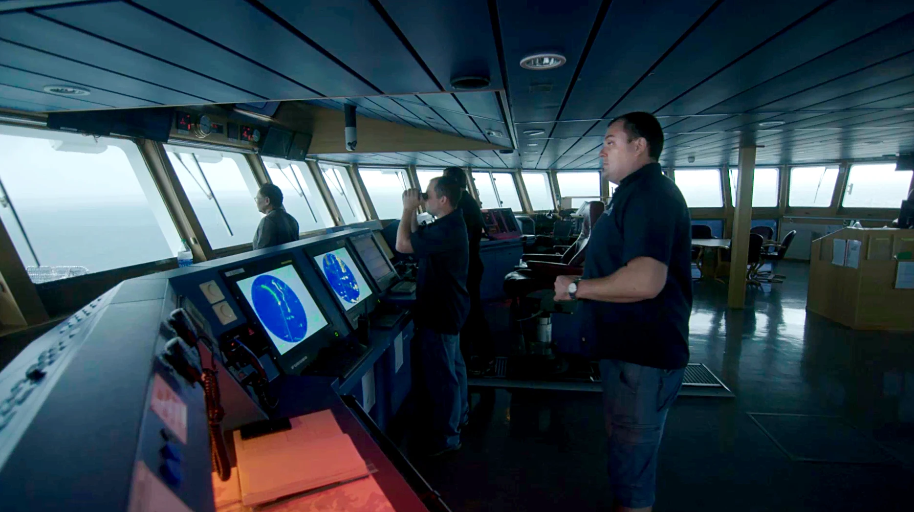 Expedition crew members stand in the bridge, overseeing operations in search of the USS Indianapolis