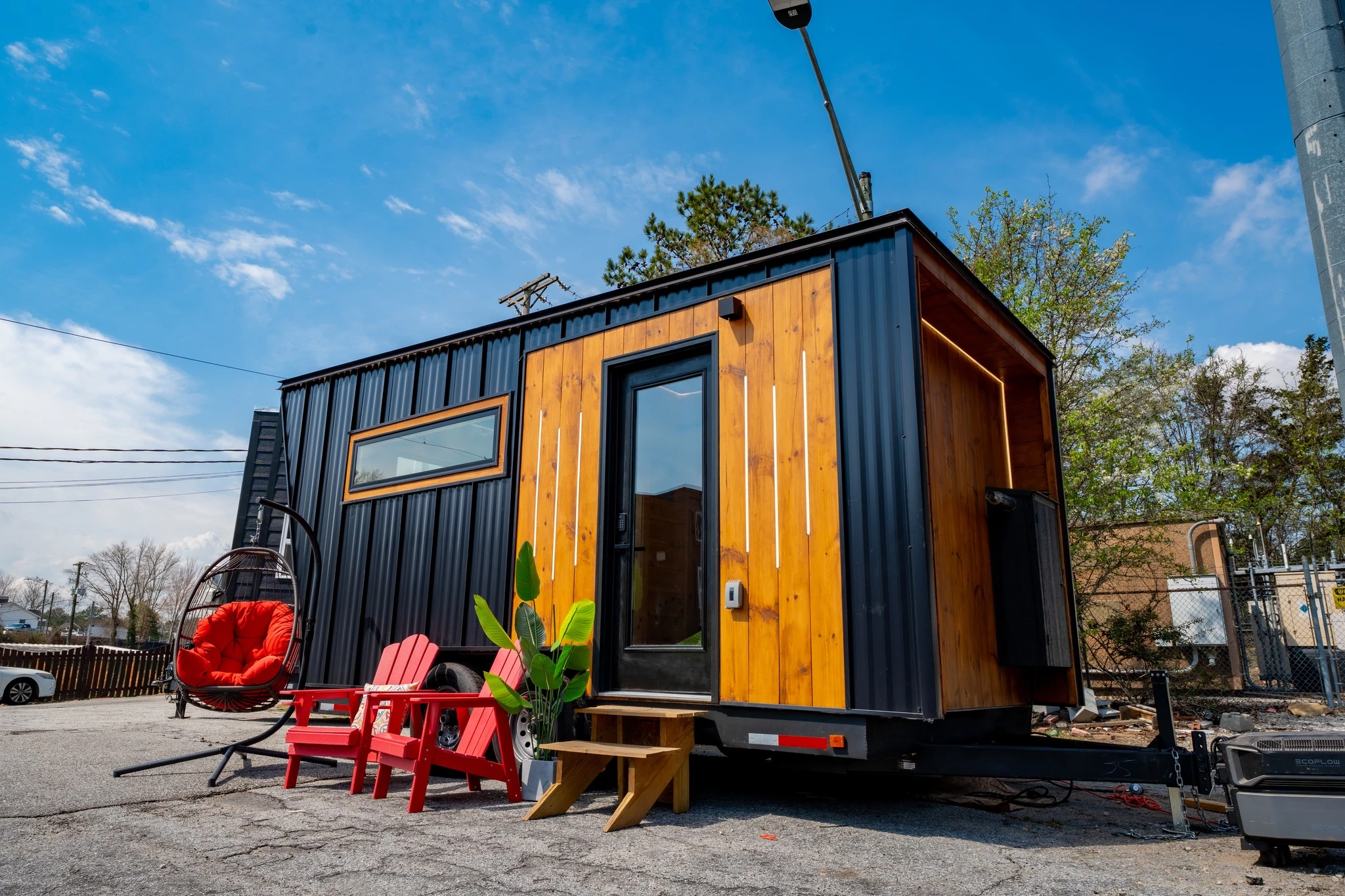 The tiny house sauna is based on a double-axle trailer and finished in black standing seam metal siding, with pine wood accenting