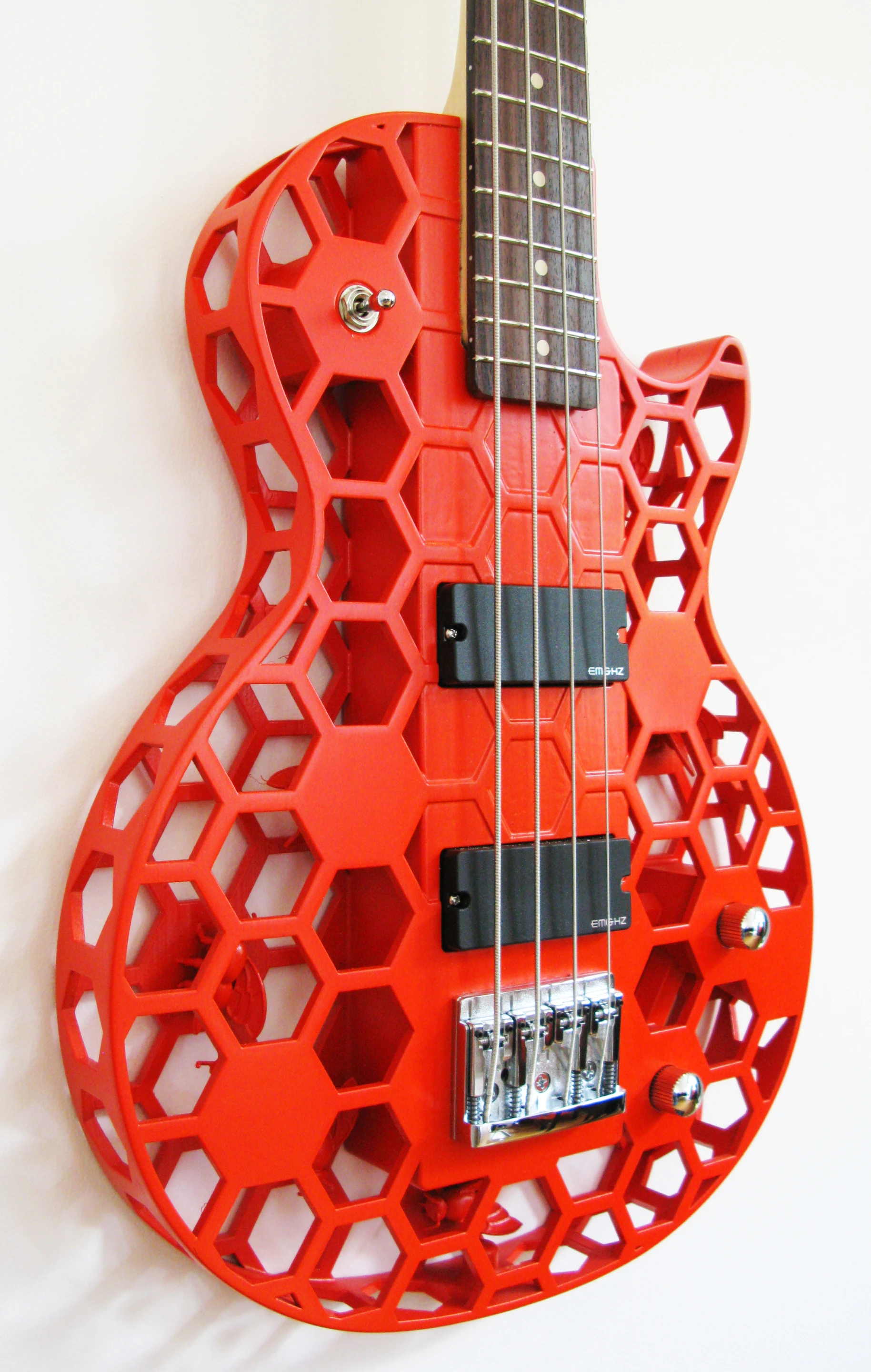 The Hive B honeycomb-styled Les Paul-shaped bass guitar has a Schaller 463 roller bridge and EMG Hz 35 passive pickups