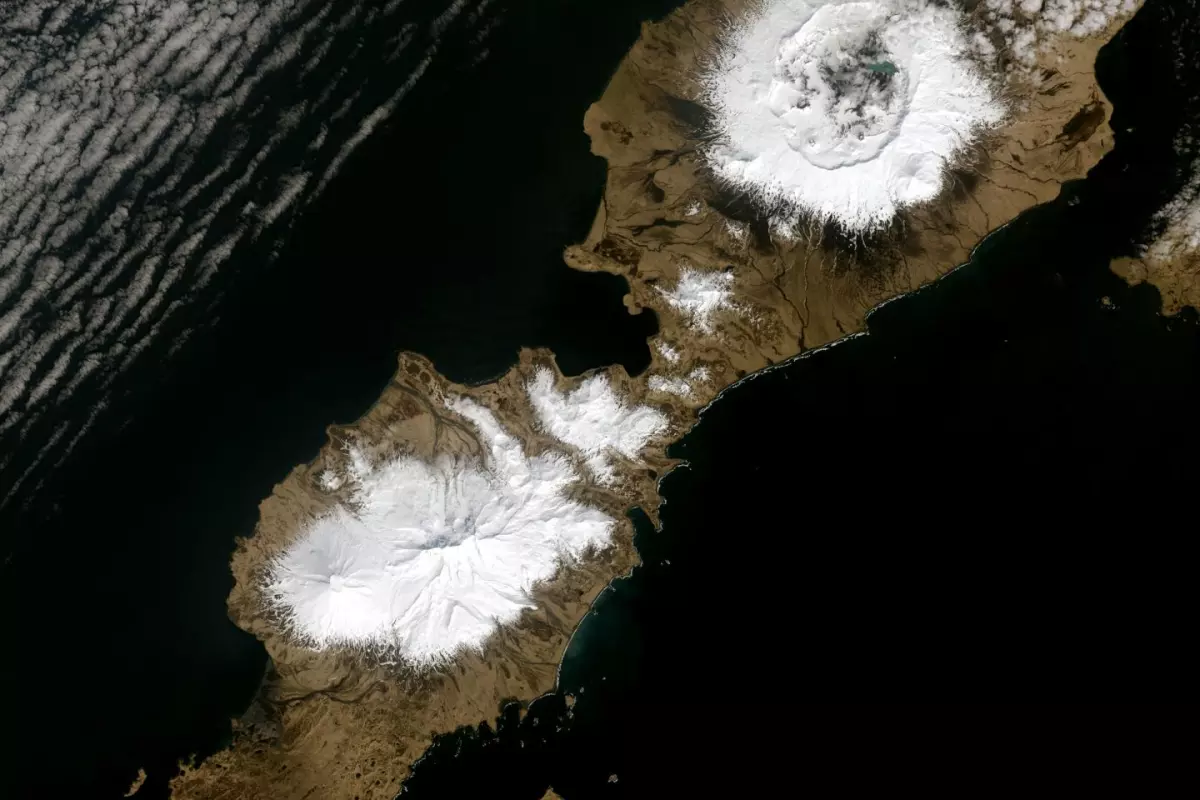 The 10-km wide caldera which formed as a result of the Okmok eruption in 43 BCE can be seen in the upper snowy region of this image
