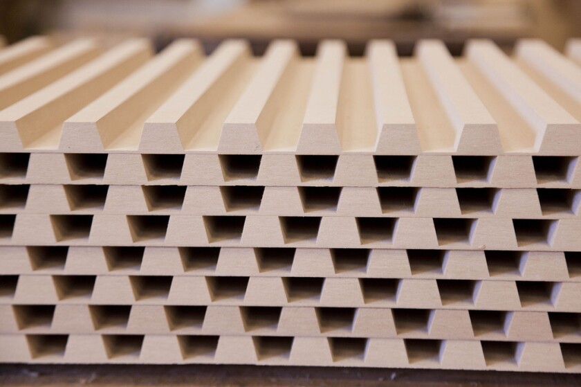 A Kuka robotic arm is used to remove portions of the MDF to leave a row of wooden teeth that interlock with another panel to form a precise curve