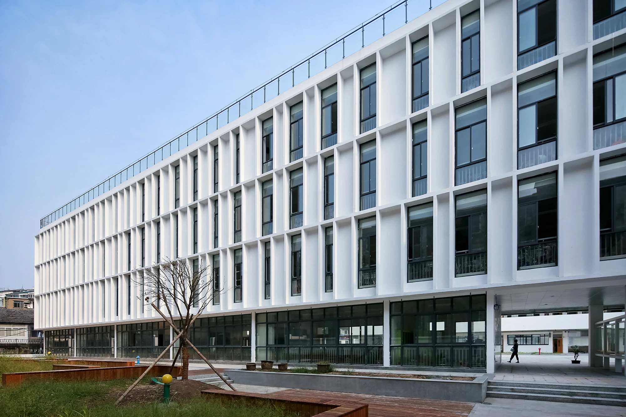 The school's façade features bands of opaque and clear glass panels