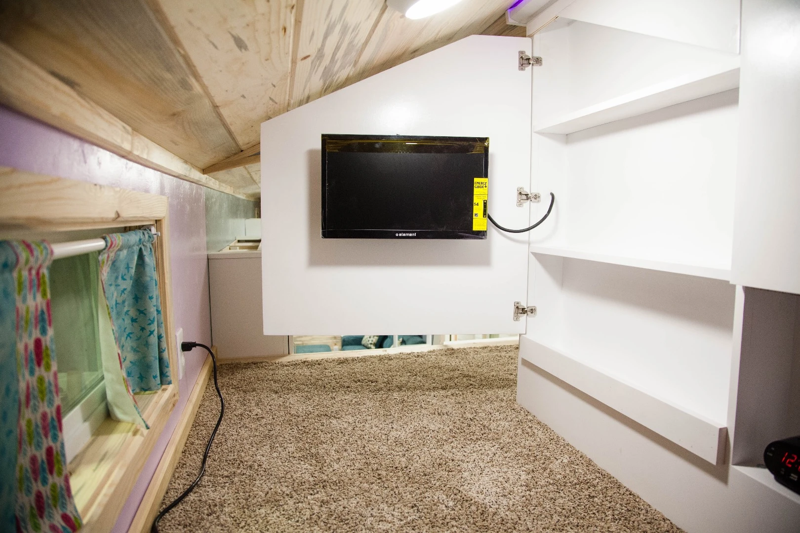A door on the dividing wall of the Brown Bear's kids sleeping loft swings open to reveal a flat screen TV and storage space