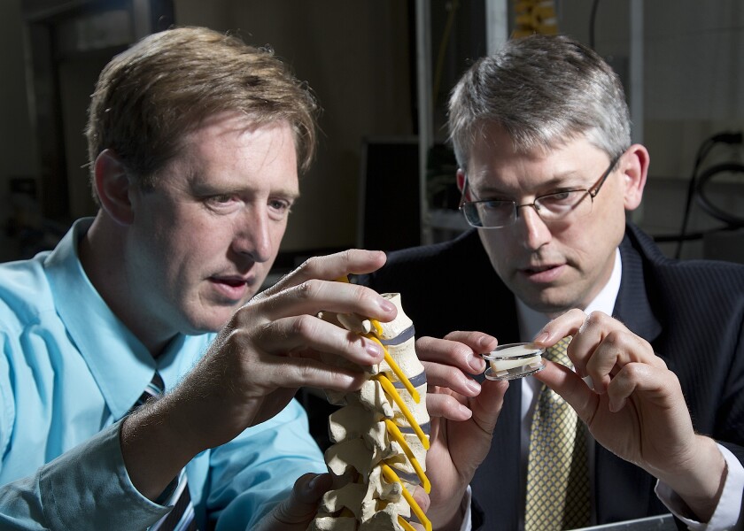 BYU engineering professors Anton Bowden (left) and Larry Howell (right) examine their artificial disc implant