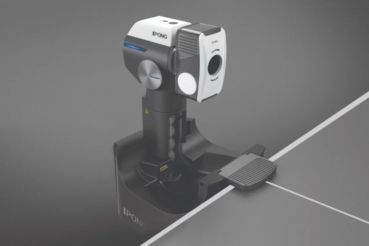 The Joola Infinity Smart Table Tennis Training Robot attaches to a table with a two-hook mechanism and comes with a catch net and ball recycling feature to keep the pong balls coming