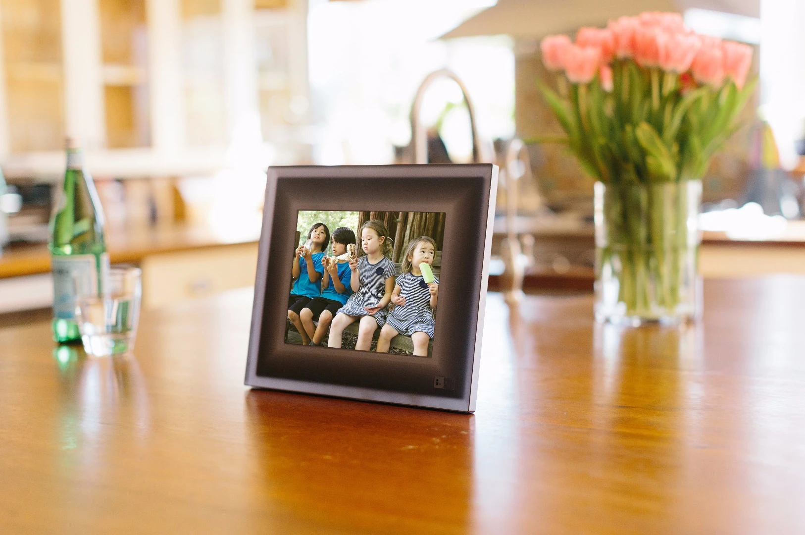 Photos are uploaded from each user's phone to the Aura cloud and relayed to the frame, which connects to the internet via Wi-Fi