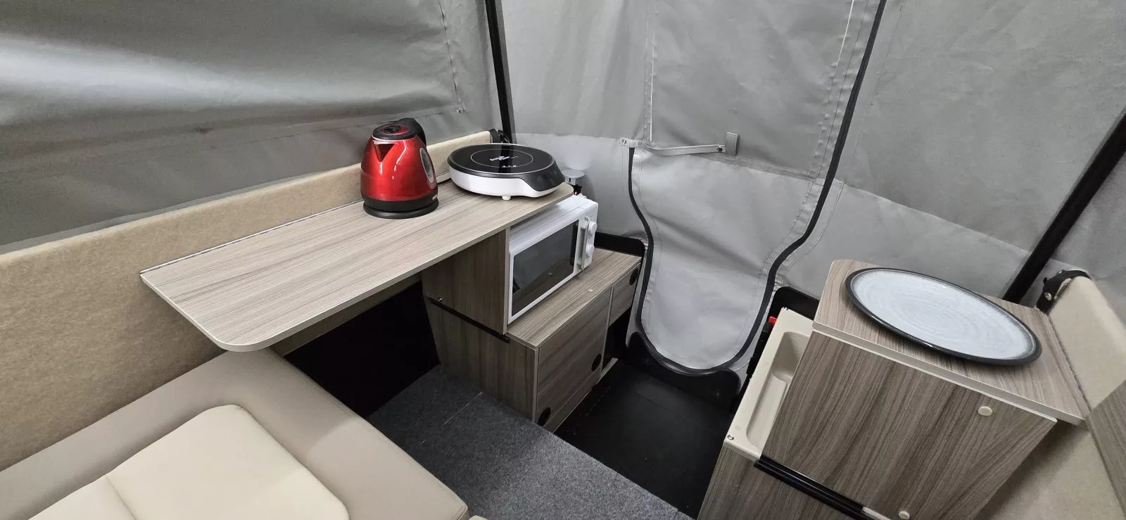 The left and right fold down shelves also serve as individual dining tables and desktops for the two campers seated in the Dashaway ECT 2 camping trailer