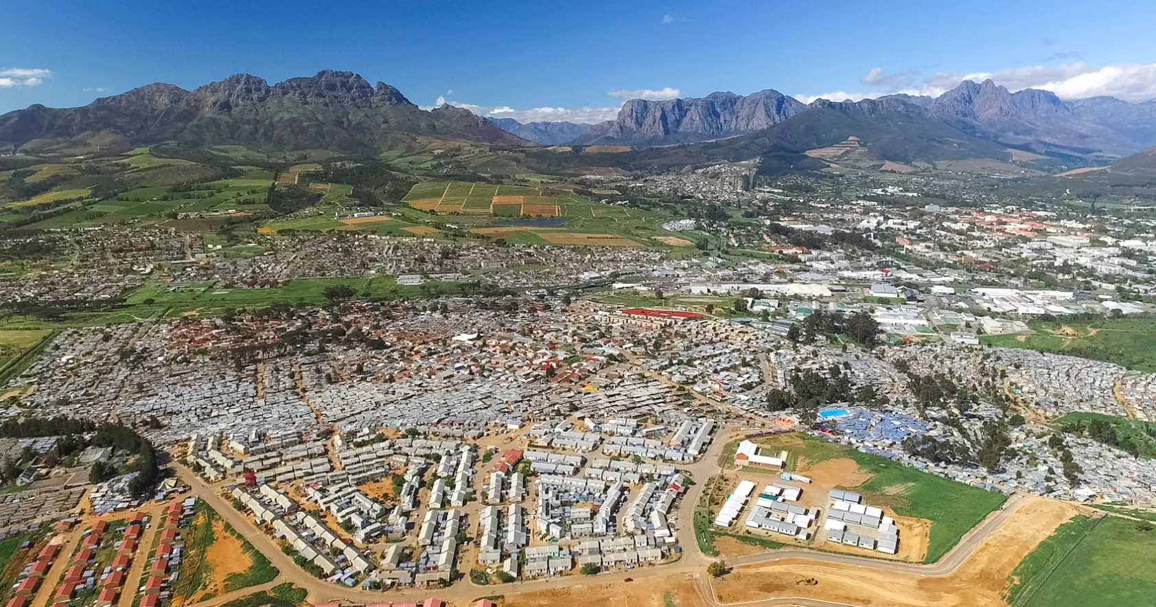Tin shacks sit in the foreground of the wine region of Kayamandi, South Africa