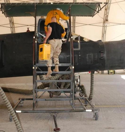 Senior Airman Duane Thompson helps Maj. Cory Bartholomew into a U-2 reconnaissance aircraft. The space suits U-2 pilots wear are bulky and limit movement, so life-support crew specialists strap the pilots into the cockpit and connect hoses and communicati