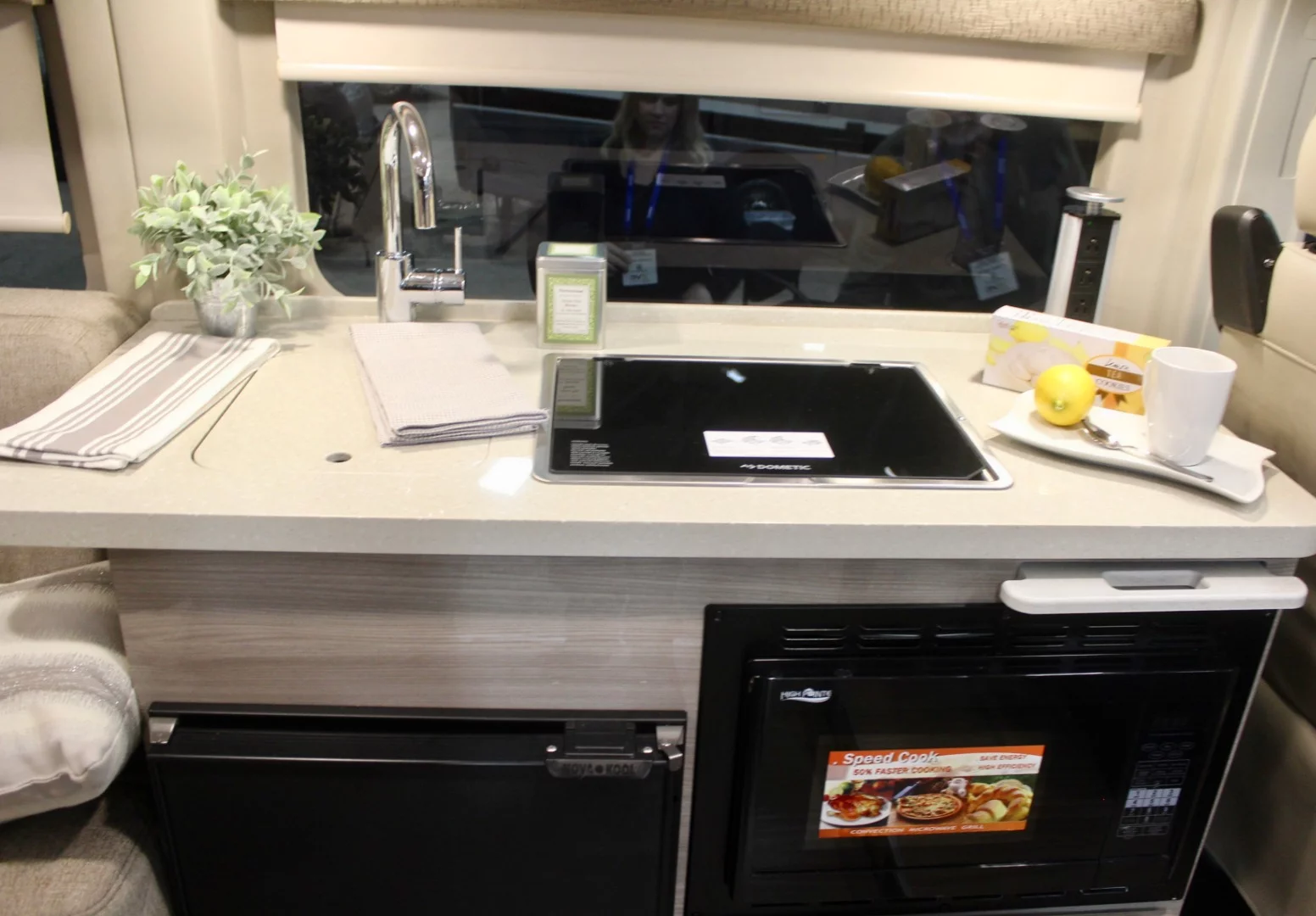 The kitchen block is fairly simple up top, with a sink and glass-top dual-burner stove, and down below it includes a fridge and microwave