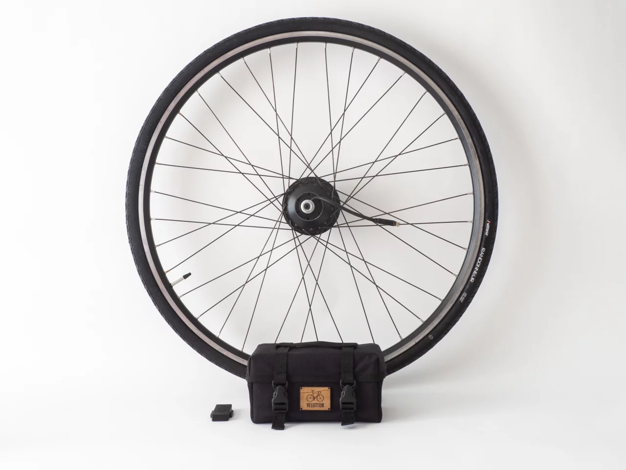 The basic Vekkit ebike conversion kit comprises a wheel rocking a hub motor, a bag that's home to the battery and electronics and a wireless cadence sensor for attaching to the pedal