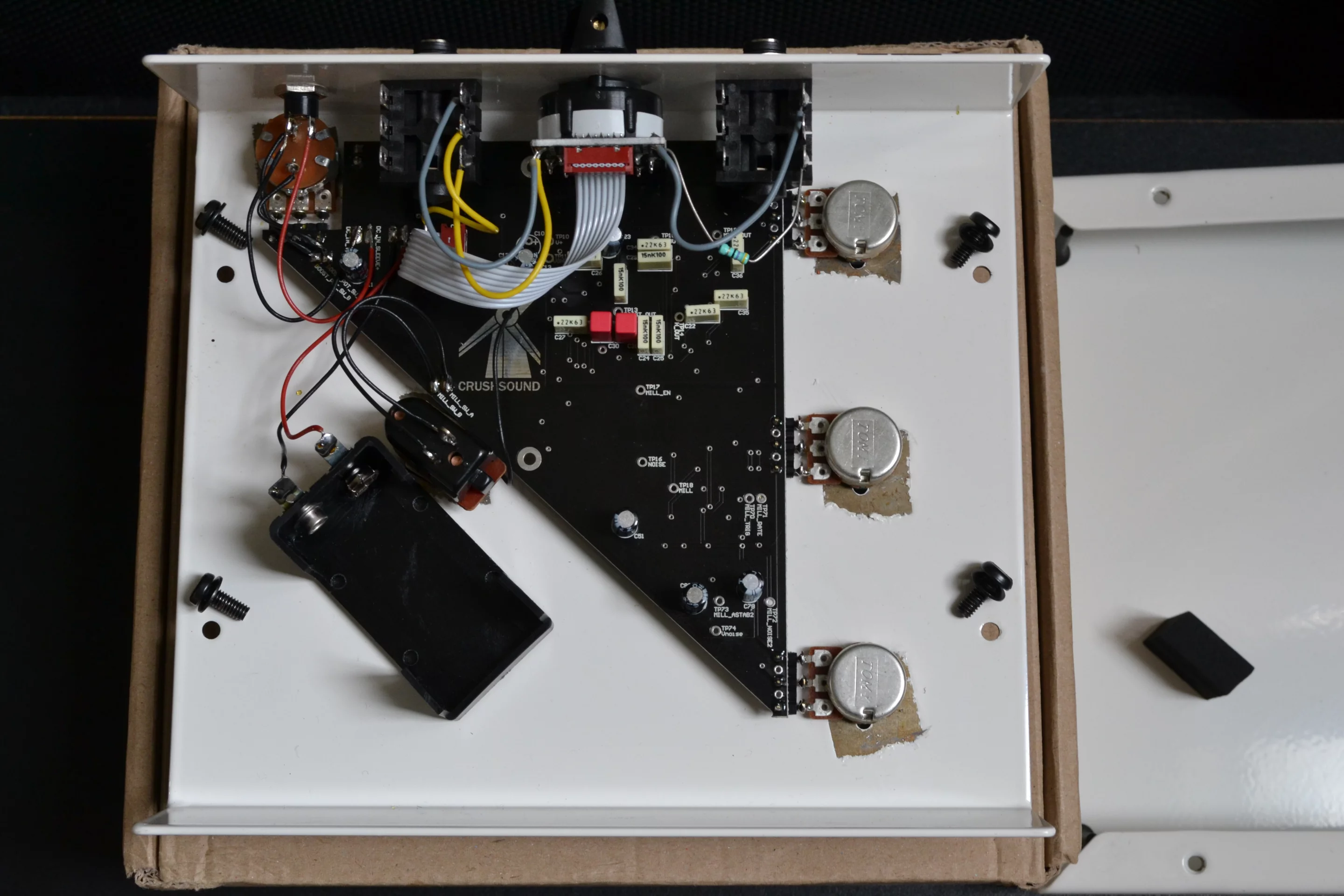 The battery compartment is positioned to the left of a triangular circuit board inside the stomp's 1.5 mm thick steel housing