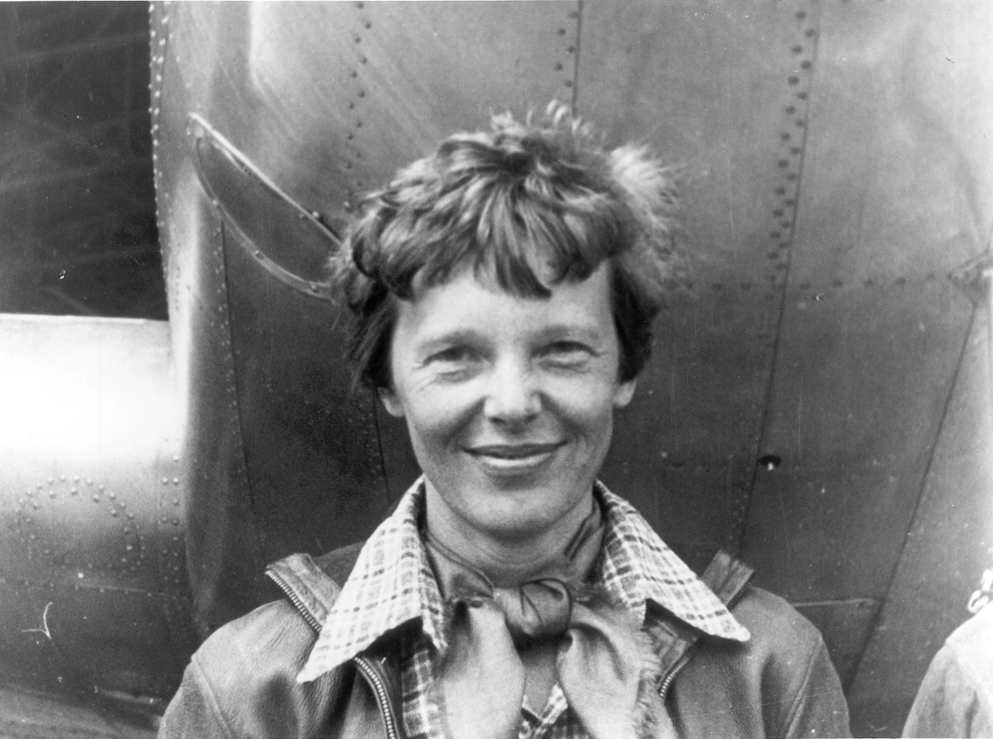 Amelia Earhart, standing under the nose of her Lockheed Model 10 Electra aircraft