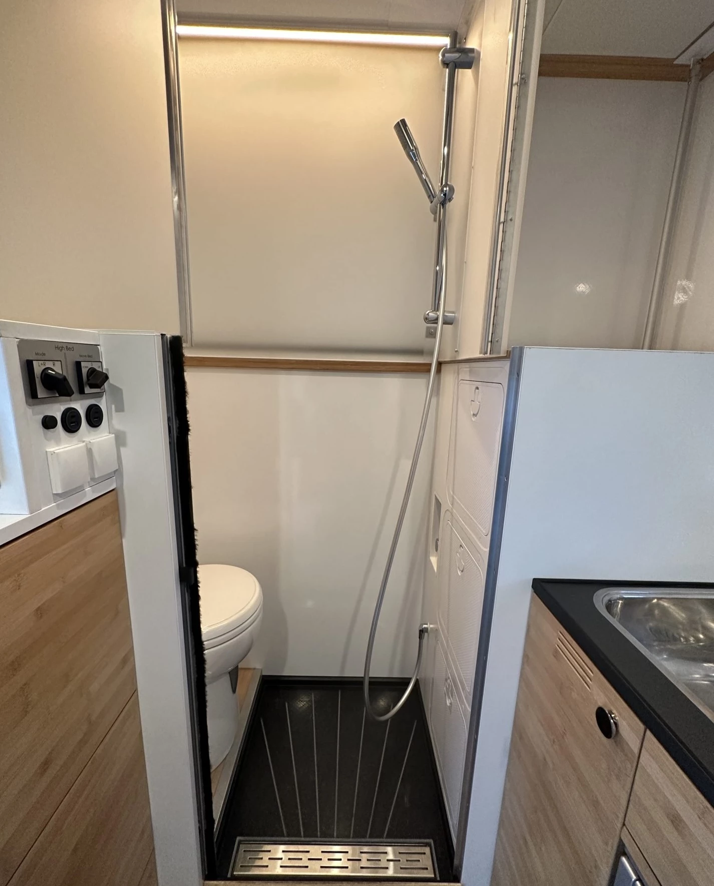 The interior bathroom is pushed against the camper's rear wall, bringing a shower and a macerator toilet