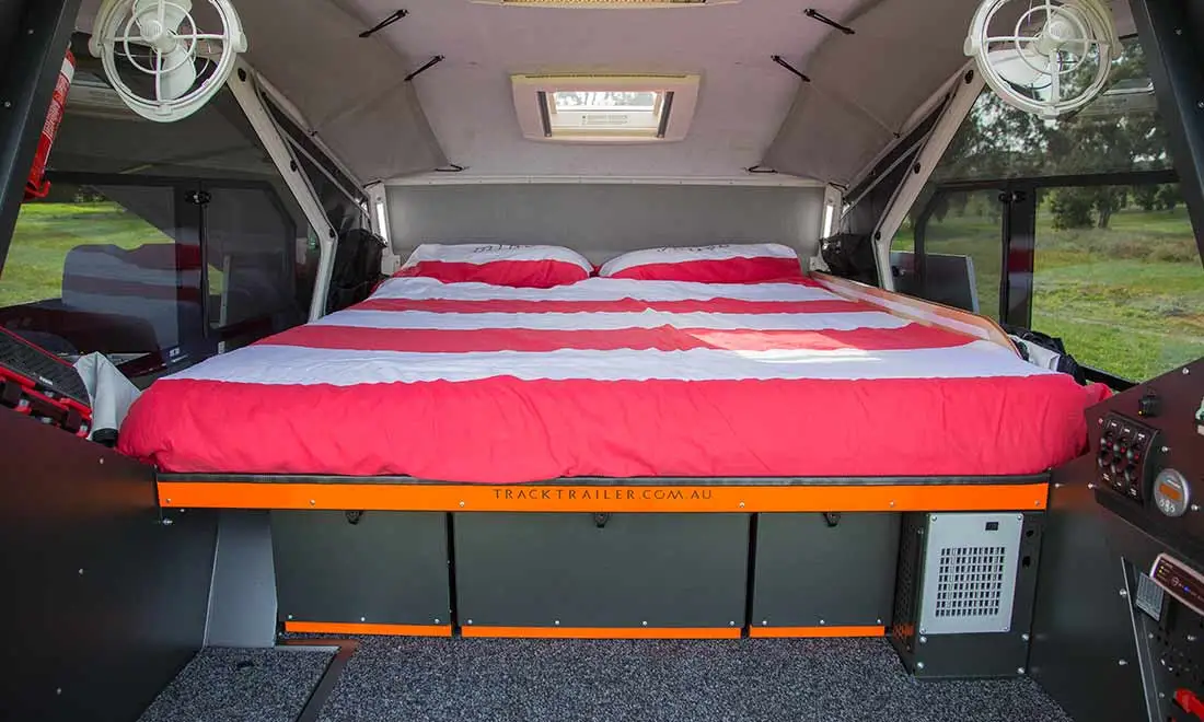 The interior includes a queen bed, sliding windows with screens and roof ventilation