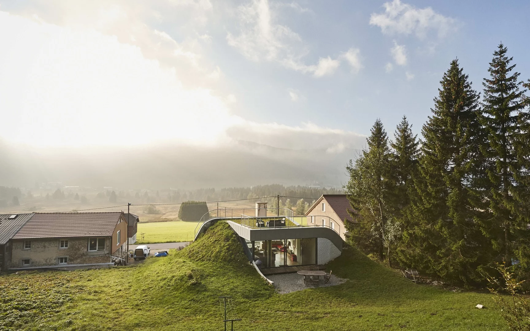 In France sits Casa Jura, a residential home built into the surrounding hill leaving just a couple of small outcrops to allow light in
