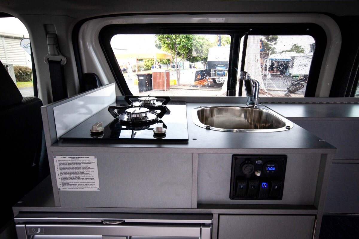 The kitchen includes a dual-burner gas stove, fridge/freezer and sink