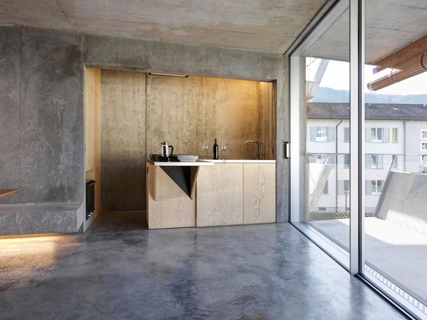 Wooden cabinetry and doors contrast with all the concrete in Affordable Housing Langgrütstrasse