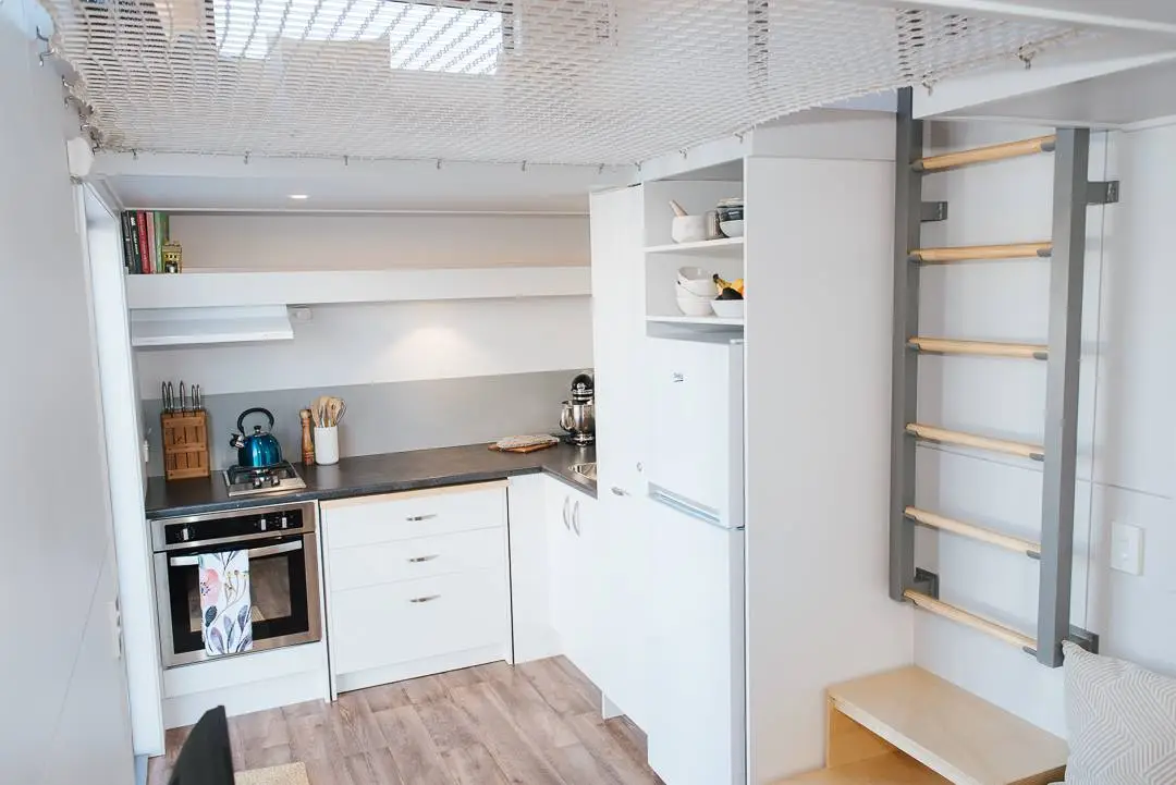 The Larissa and Tyler Tiny House's kitchen includes an oven and two-burner propane-powered stove