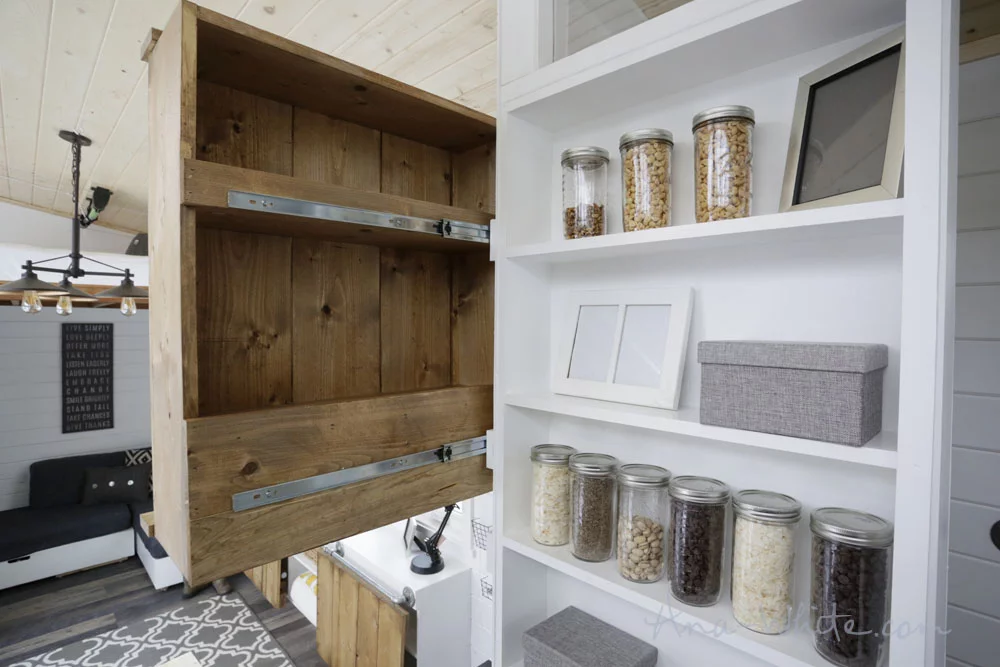 This storage cabinet in the Open Concept Rustic Modern Tiny House's main living area slides for easier access from the kitchen