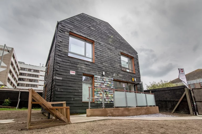Waste House features 20,000 toothbrushes, 4,000 DVD cases, 2,000 floppy discs, and 2,000 used carpet tiles, used to clad the home's facade (Photo: BBM)