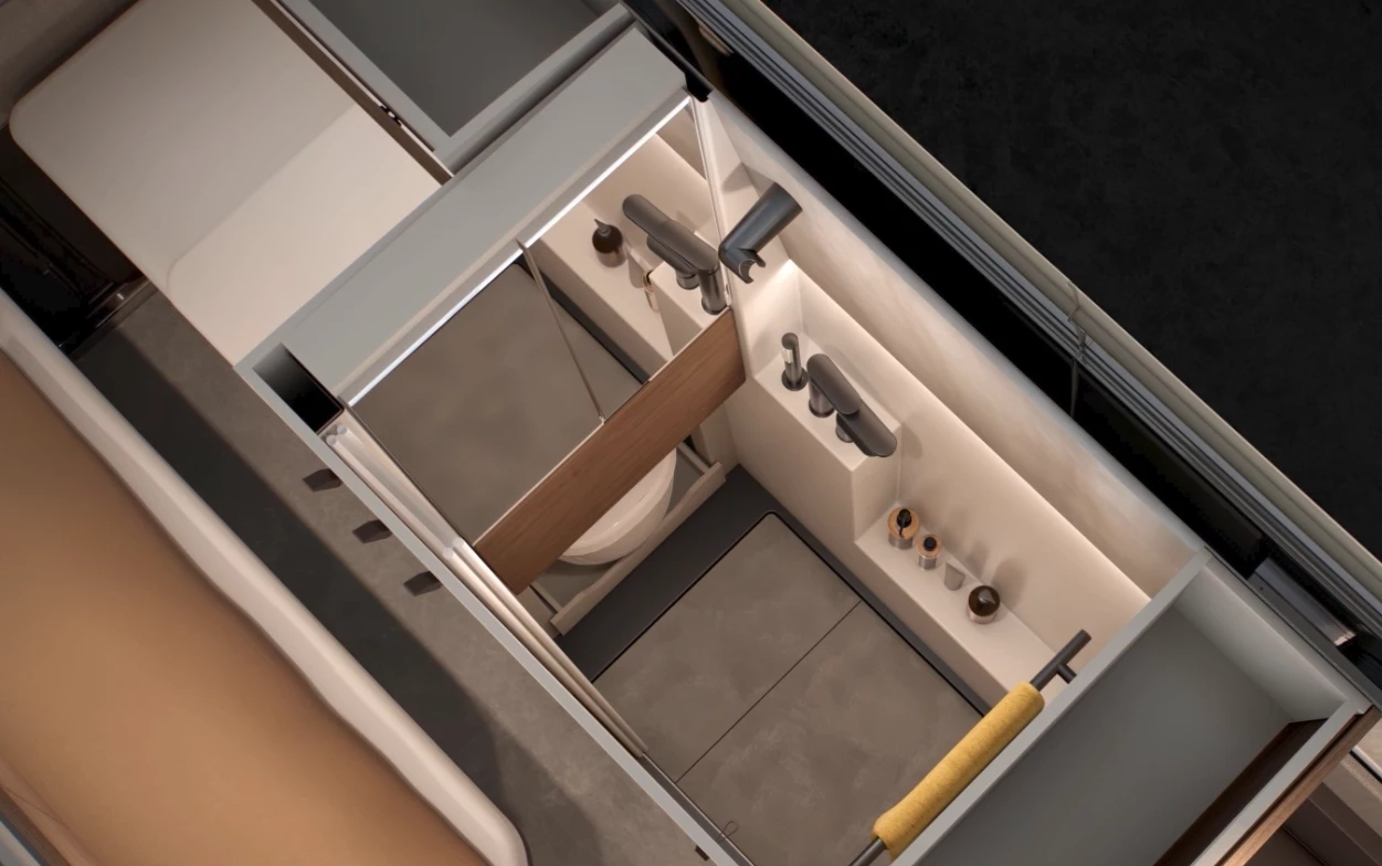 The sink basin folds up flush into the vanity wall, showing the slide-out toilet peeking out from below