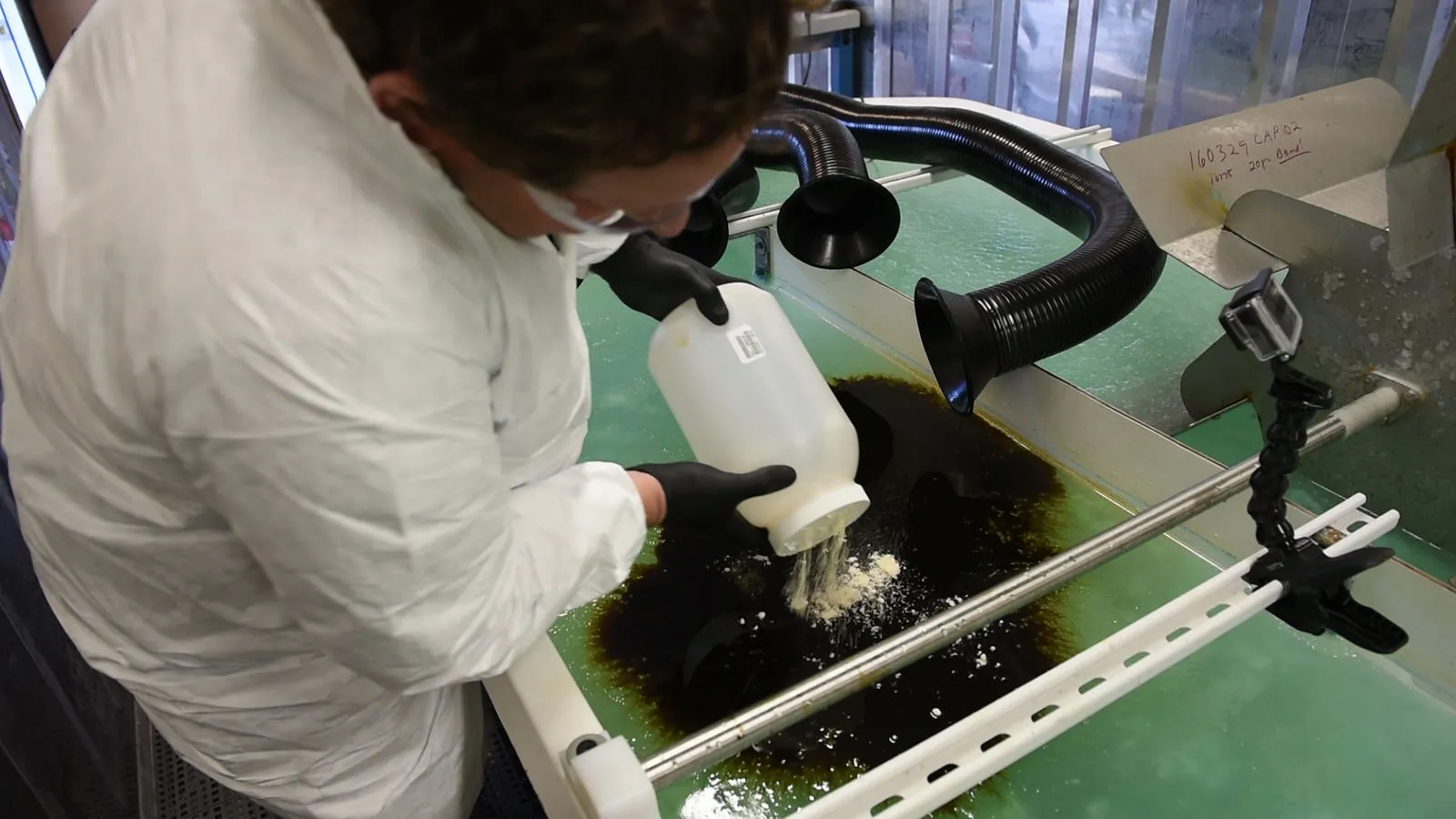 A PNNL researcher puts the chemically modified sawdust to work on a small oil spill inside a lab that mimics the Arctic's icy conditions