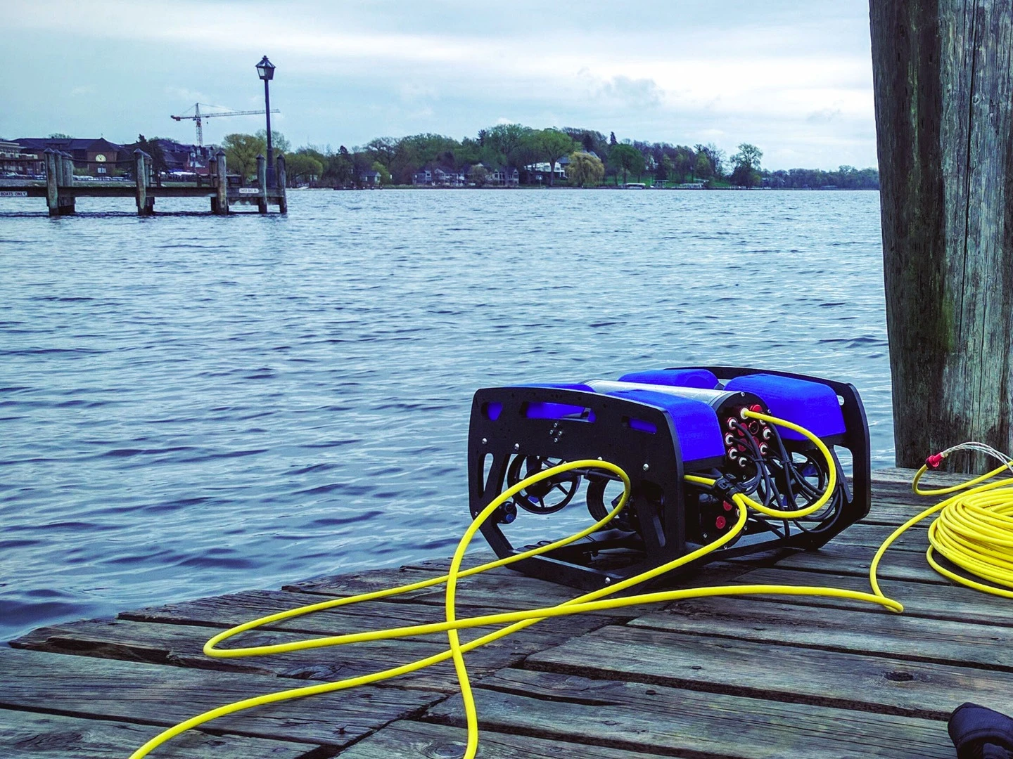 An umbilical tether runs from the BlueROV2 to a topside laptop or tablet, where the user controls it in real time using the QGroundControl app