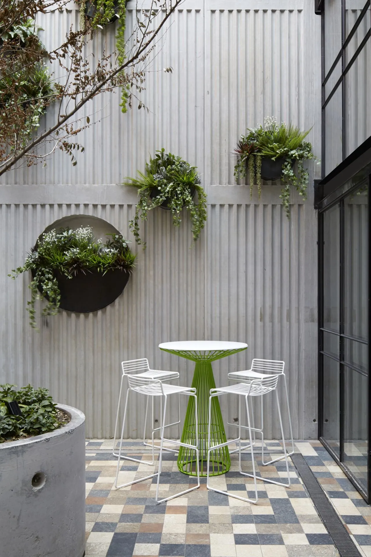 The interior courtyard boasts a concrete slab wall freckled with hanging plants