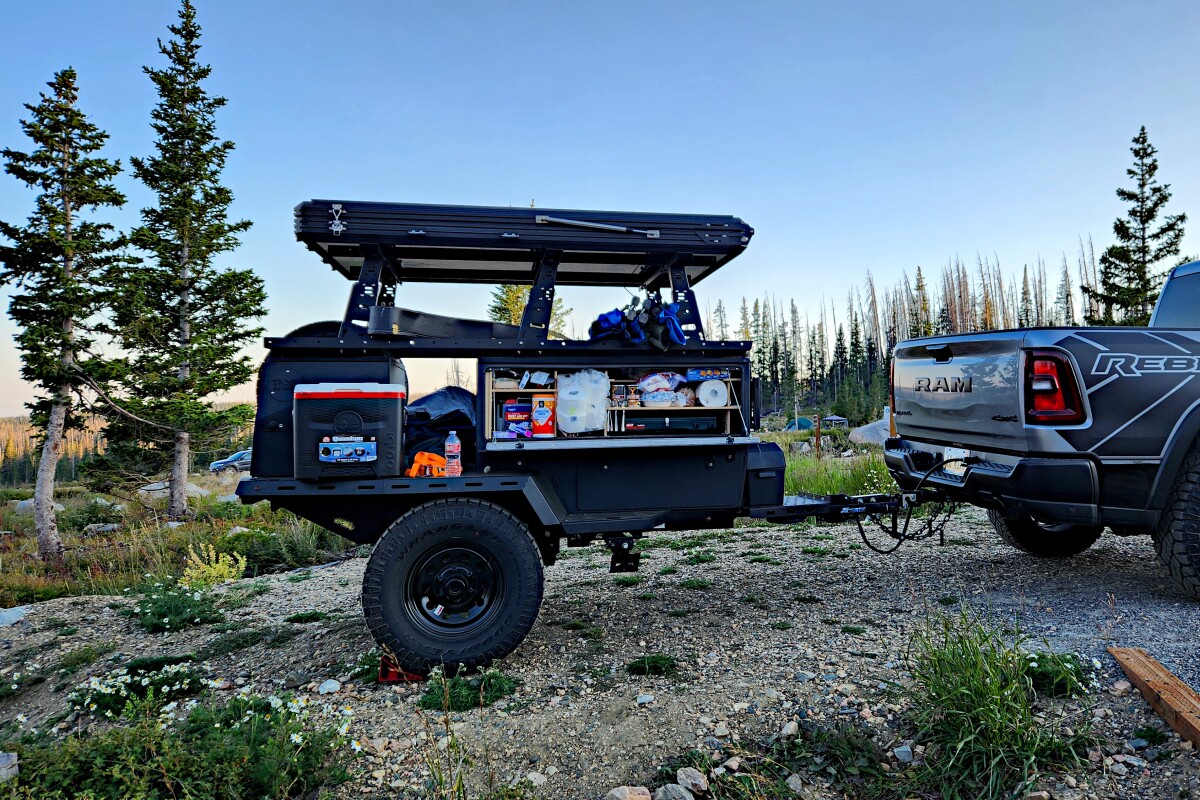The Taxa Outdoors Woolly Bear Overland camp trailer, with its galley and an extra cooler open for snacks during camp setup