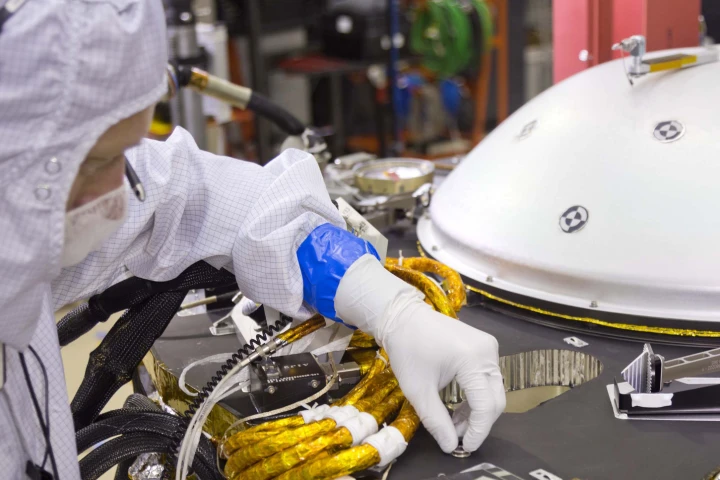 A spacecraft specialist affixes a dime-size chip onto the lander deck in November 2015