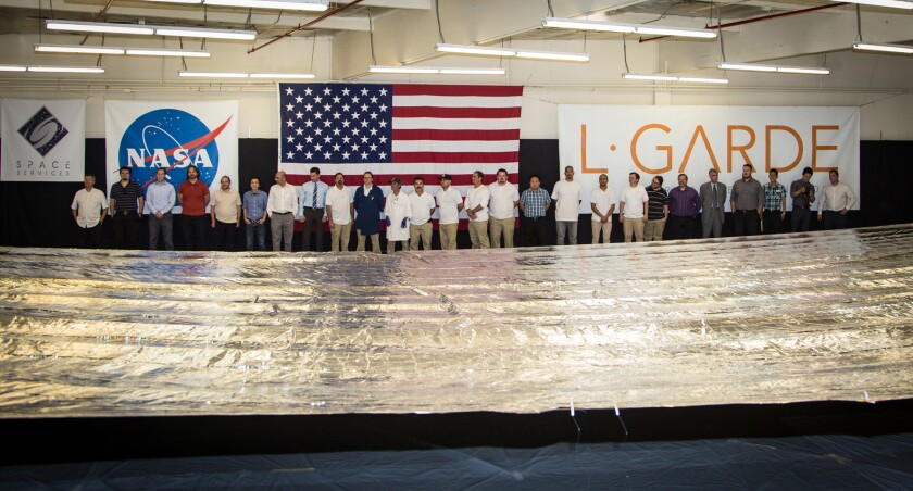 Team members, NASA partners, and students pose with the deployed solar sail