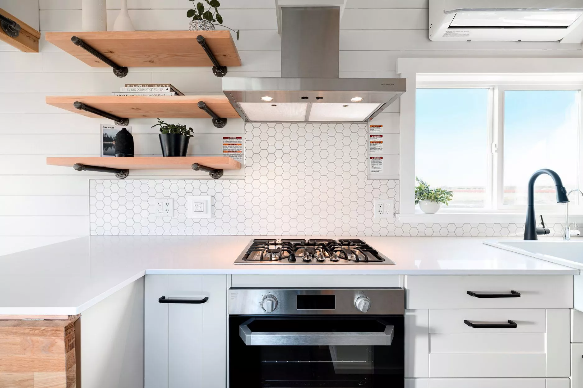 The 34ft Eco-Friendly Tiny House RV's kitchen includes a three-burner propane-powered cooktop and oven