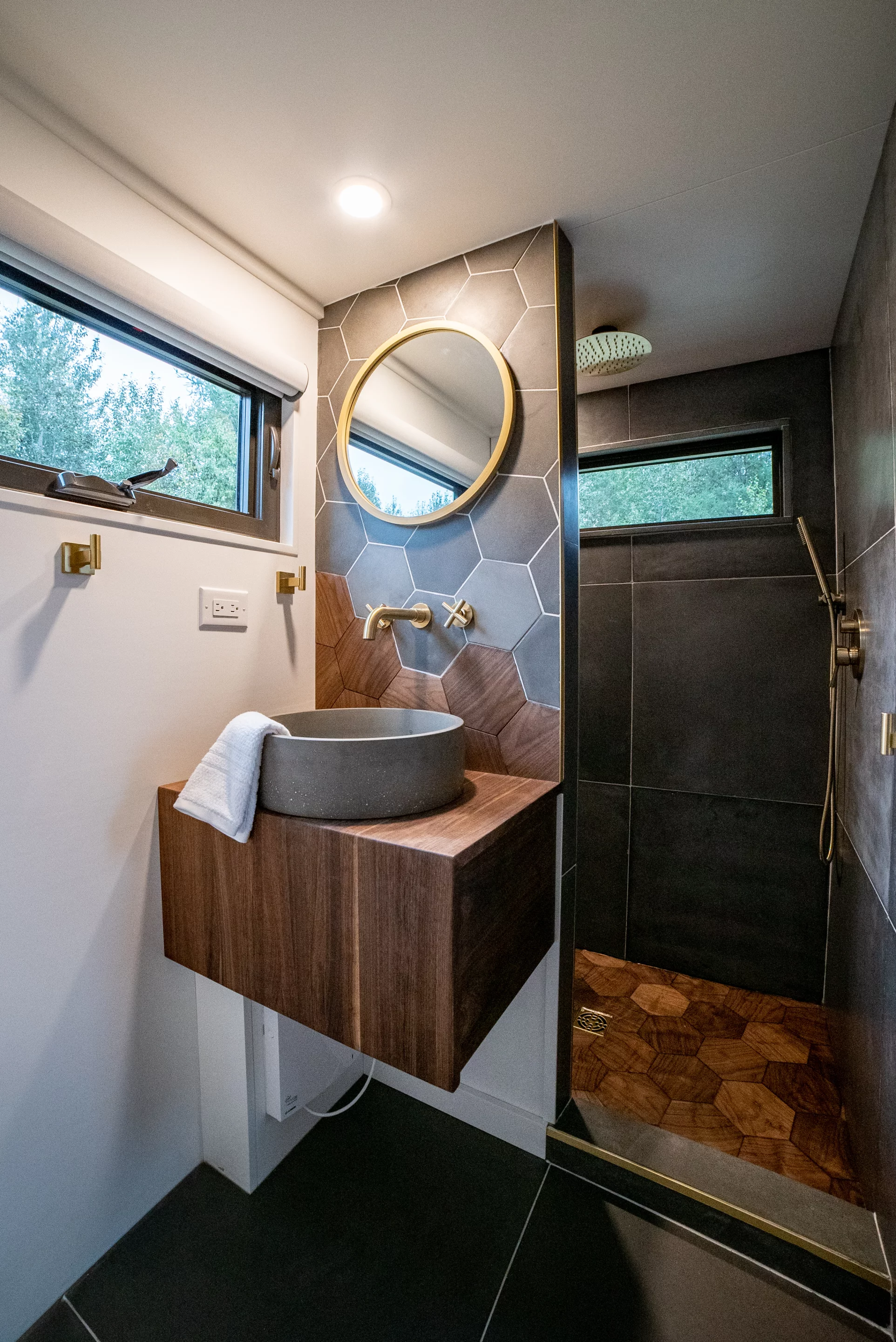 The Trahan Tiny House's bathroom is tastefully finished in walnut, concrete, and tiles, and includes a sink, shower, and toilet
