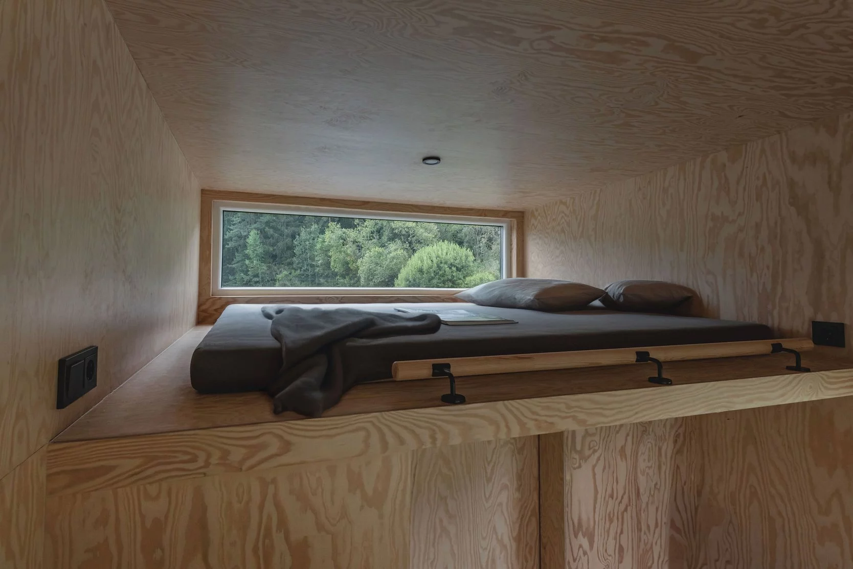 The BTH Loft off-grid's upstairs bedroom is a typical loft space with a low ceiling and a double bed