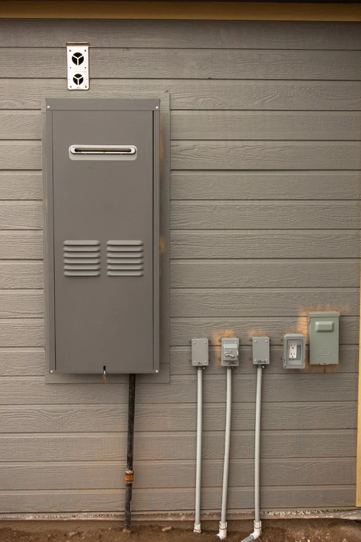 Chris has a standard Atwood RV style furnace installed in the wall for heat. It runs from two 30 gallon propane tanks housed outside near the shipping container. Also shown are the conduits and connections for the power running from the shipping container to his tiny home.