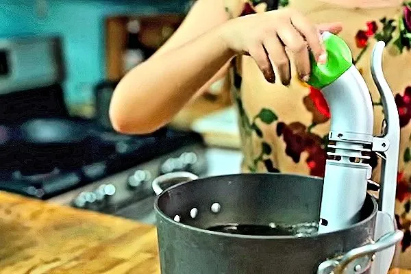 The Nomiku sous-vide immersion circulator in use clamped to the side of a pot